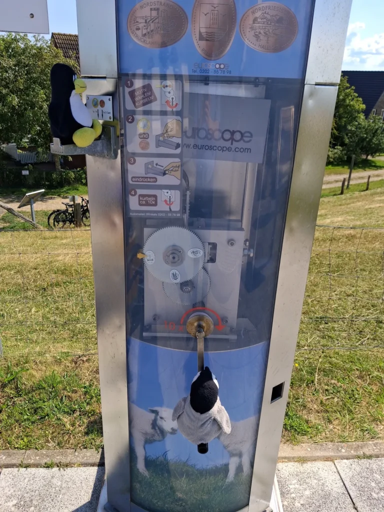 Mütux dreht die Krubel des Presspenniautomaten und Neville wirft oben das Geld rein