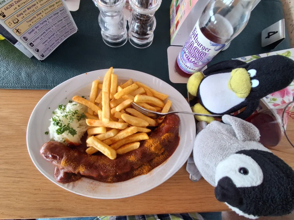 Neville und Mütux essen eine Riesencurrywurst mit Pommes und Salat