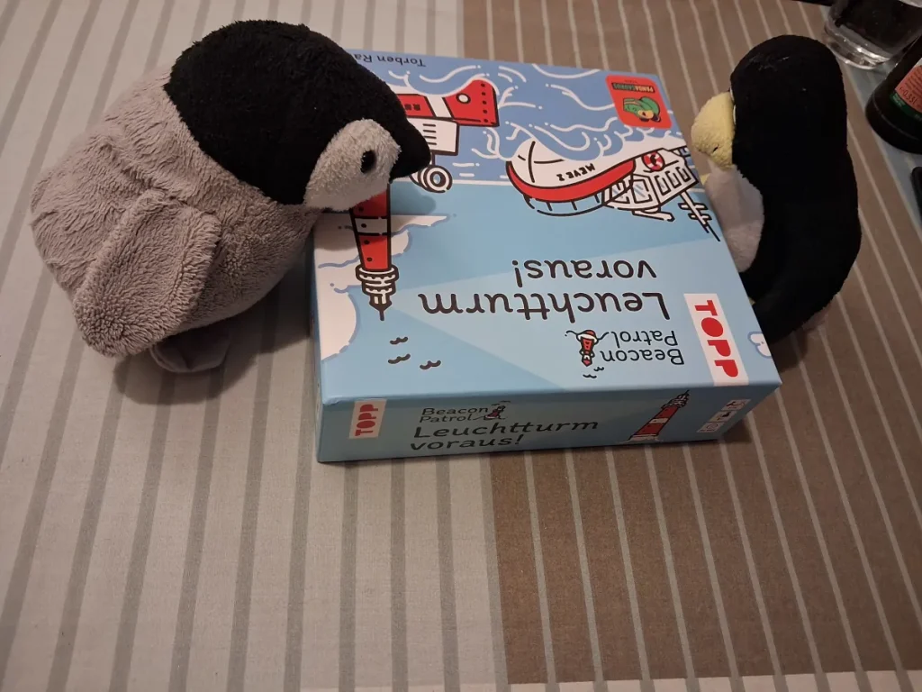 Neville und Mutüx schauen auf das Spiel Leuchtturm vorraus im Karton
