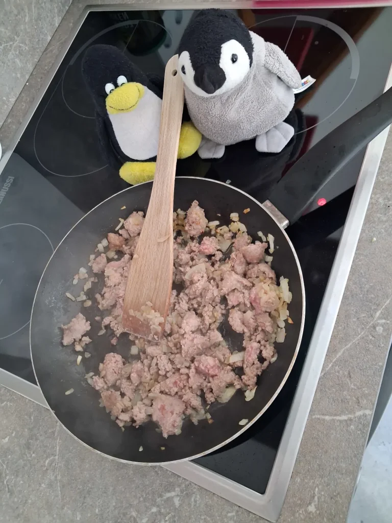 Pinguine braten Fleisch an
